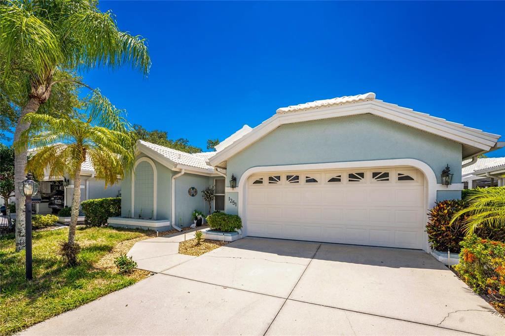 A covered outdoor patio with tile flooring overlooks a small swimming pool and screened enclosure — 1251 HARBOR TOWN WAY, VENICE, FL