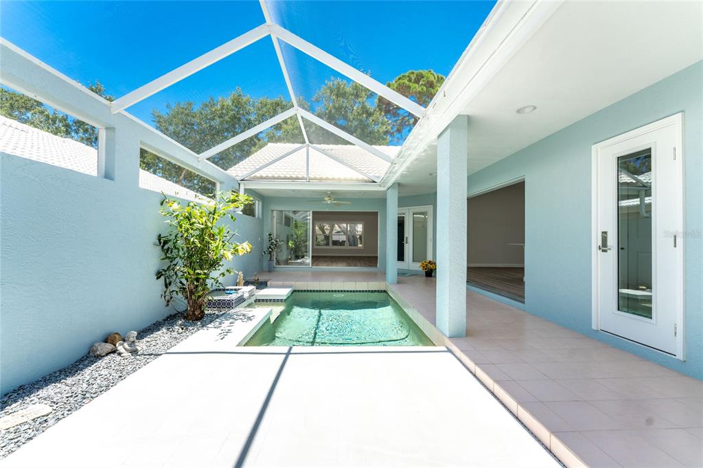 A covered patio features a swimming pool with a fountain and a screened-in enclosure — 1251 HARBOR TOWN WAY, VENICE, FL