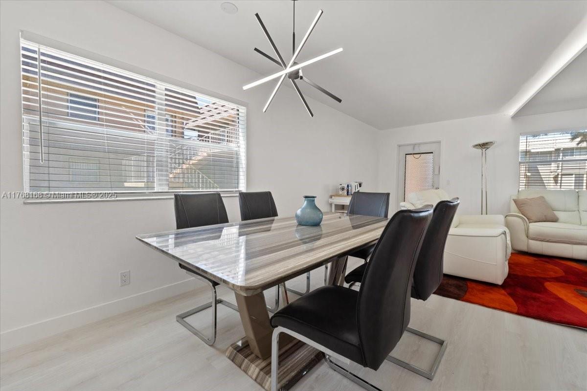 A dining room features a modern chandelier, a striped table, and black chairs — 590 Brittany M # 590, Delray Beach FL 33446, DELRAY BEACH, FL