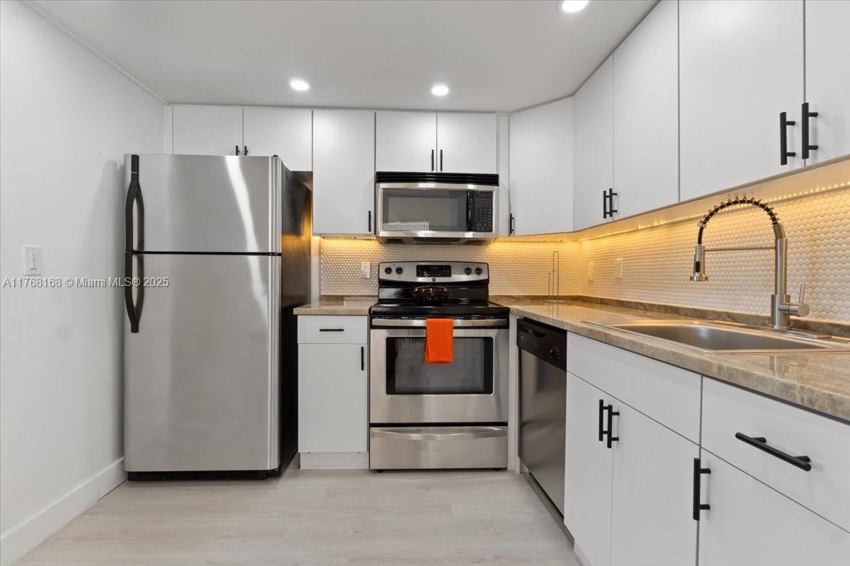A modern kitchen features white cabinets, stainless steel appliances, and a tiled backsplash — 590 Brittany M # 590, Delray Beach FL 33446, DELRAY BEACH, FL