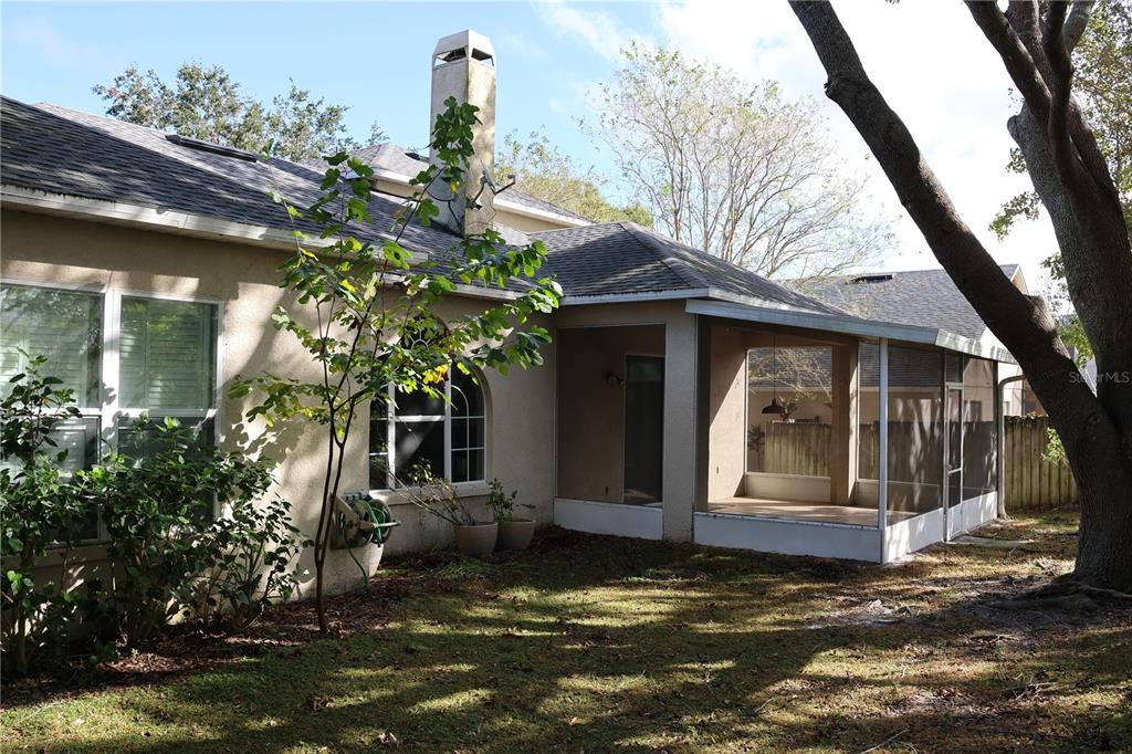 The exterior of a house features a stucco wall, a chimney, and a screened-in porch — 1730 TEALBRIAR AVENUE, OVIEDO, FL
