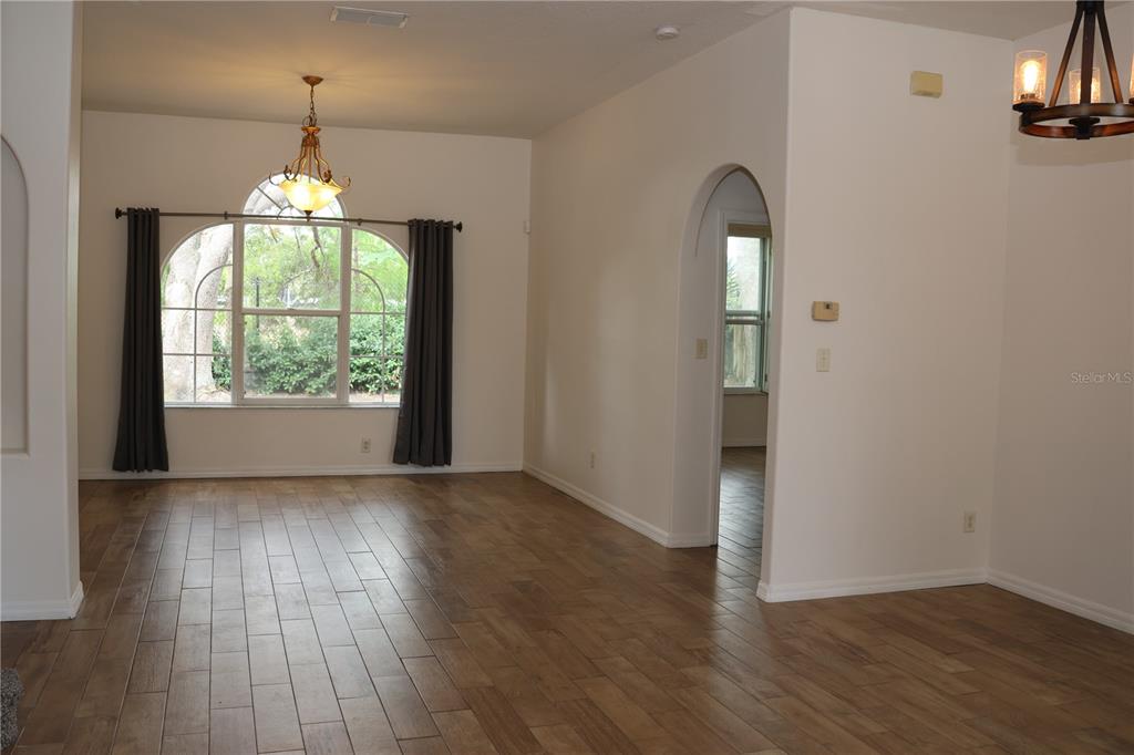 A dining room with wood-look tile floors, an arched doorway, and a large window — 1730 TEALBRIAR AVENUE, OVIEDO, FL