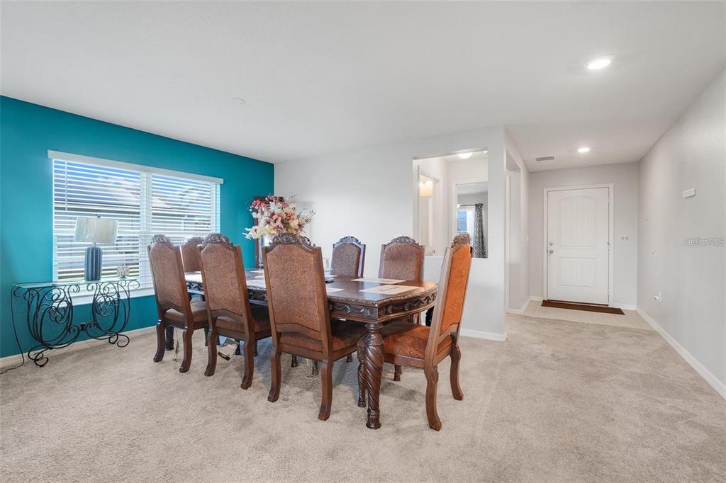 A dining room features a dark wood table with six chairs and a teal accent wall — 2111 FICUS STREET, MASCOTTE, FL