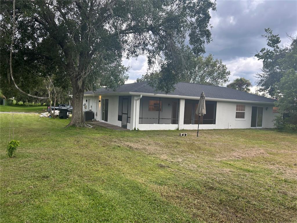 A white house with a screened-in porch and a large tree in the yard — 620 MIDIRON DRIVE, KISSIMMEE, FL