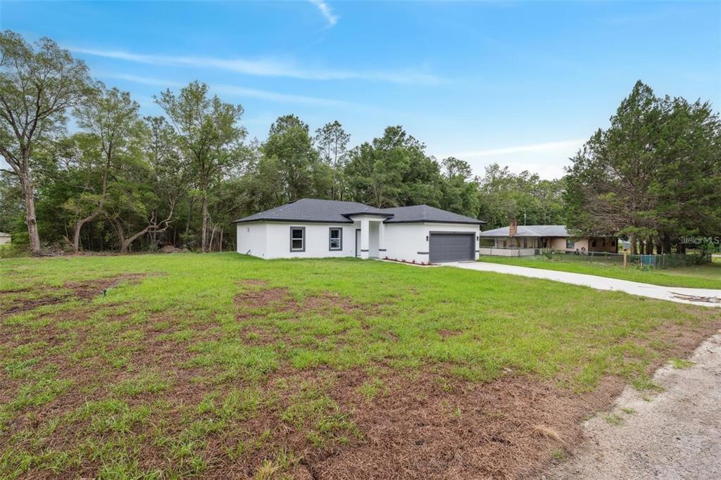 A white single-story house with a dark roof and garage sits on a grassy lot — 732 W MACROY PLACE, CITRUS SPRINGS, FL