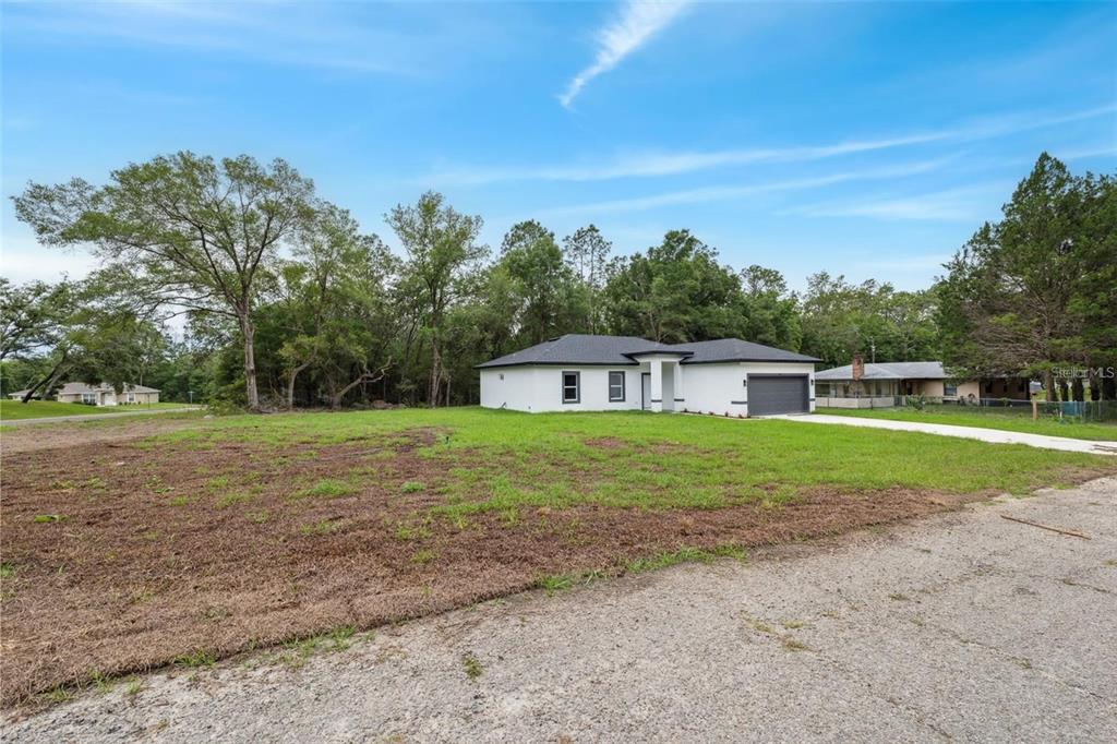A white, single-story house with a dark roof and garage sits on a grassy lot — 732 W MACROY PLACE, CITRUS SPRINGS, FL