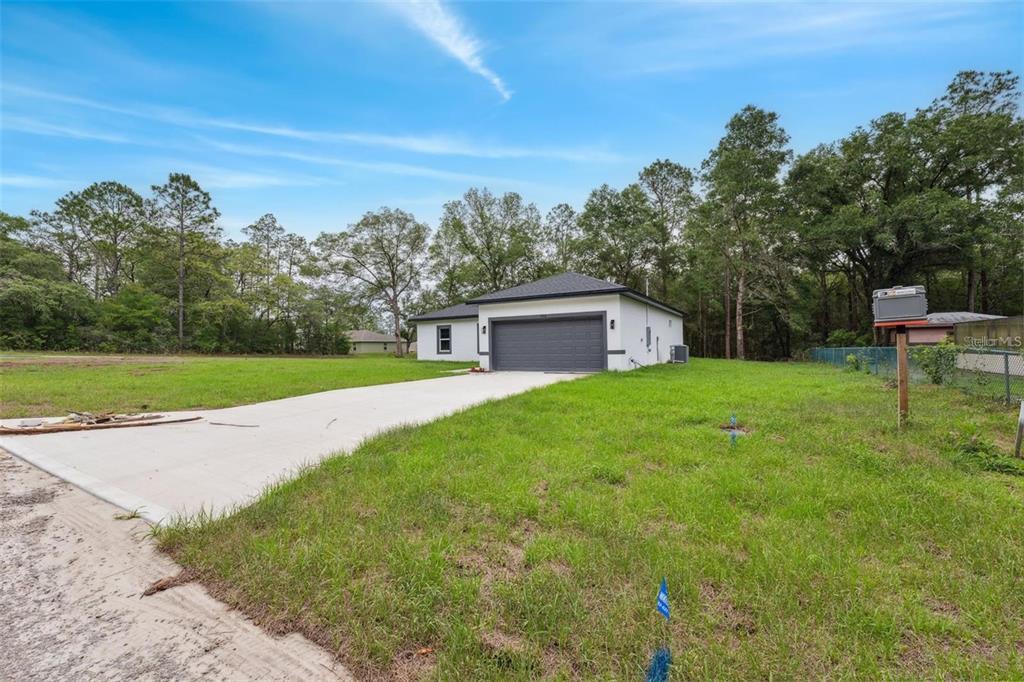 A single-story white house with a dark roof and a concrete driveway sits on grass — 732 W MACROY PLACE, CITRUS SPRINGS, FL