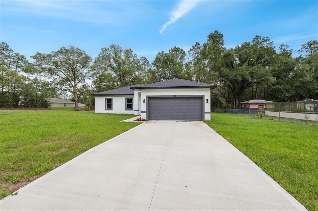 A single-story house with a white exterior, dark roof, and a two-car garage — 732 W MACROY PLACE, CITRUS SPRINGS, FL