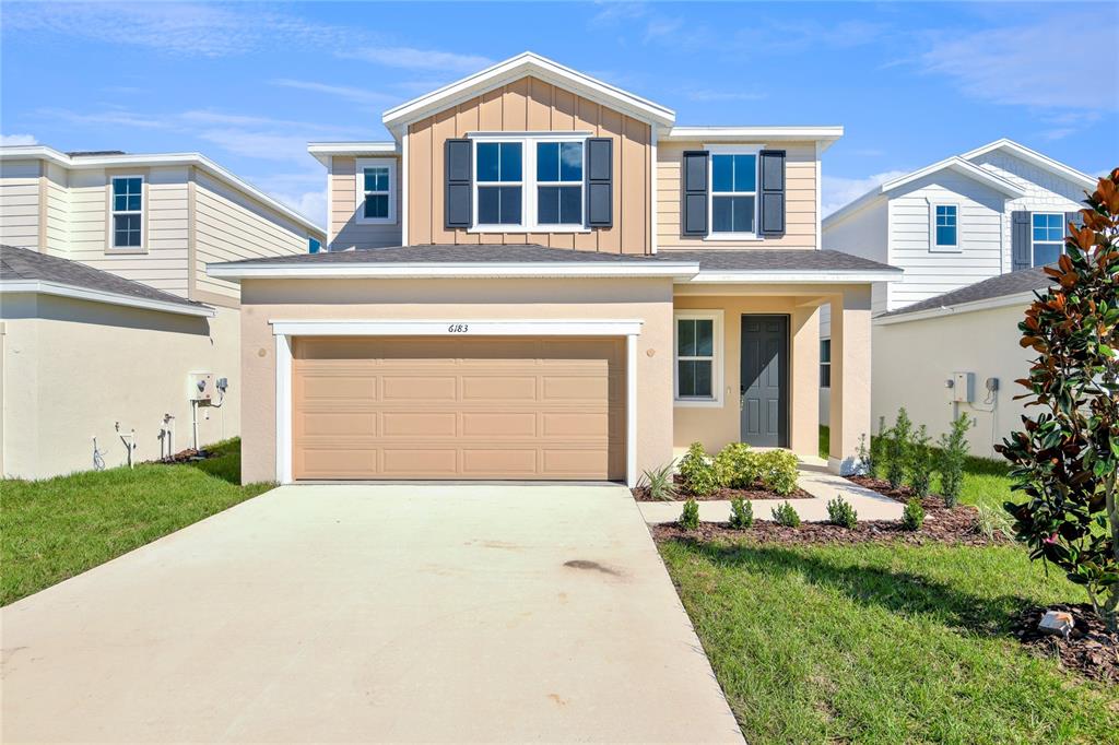 A two-story suburban house with a tan stucco exterior, a two-car garage, and a driveway — 6183 SW 64TH TERRACE, OCALA, FL