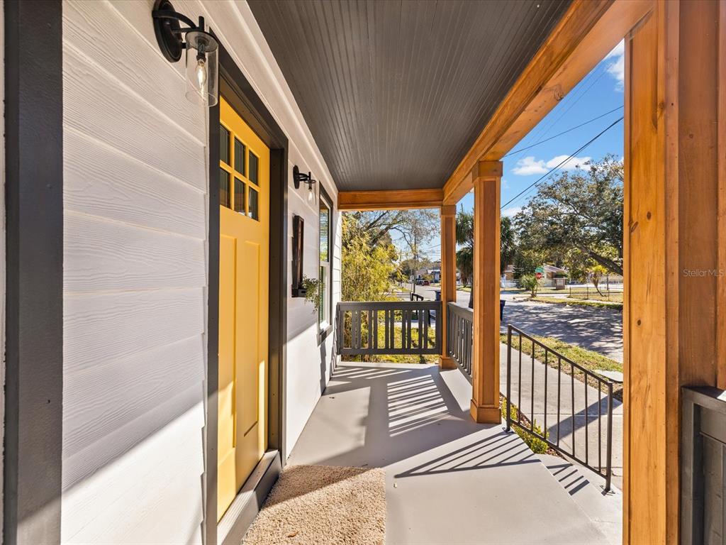 A single-story house with a front porch, wooden pillars, and a yellow door at sunset — 2107 W CHERRY STREET, TAMPA, FL