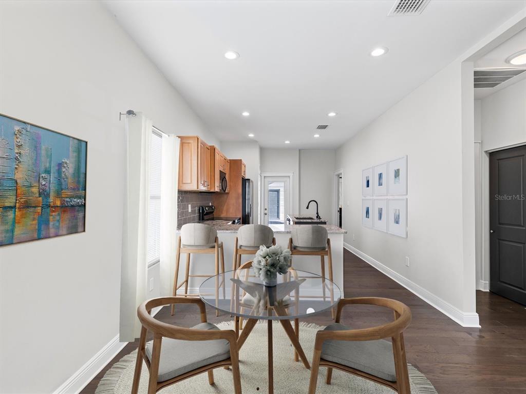 A kitchen features light wood cabinets, granite countertops, a black island, and dark wood flooring — 2107 W CHERRY STREET, TAMPA, FL