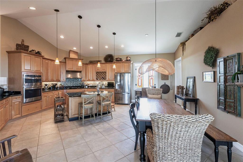 A kitchen and dining area with wood cabinets, stainless steel appliances, and tile flooring — 3712 BALBOA COURT, PUNTA GORDA, FL