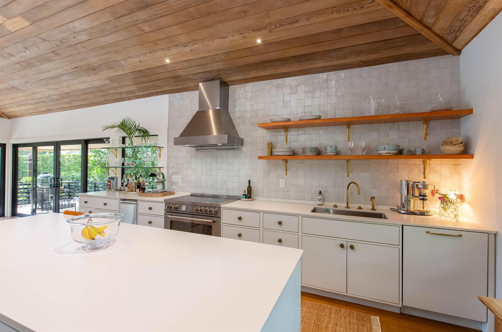 A modern kitchen features white cabinets, open wood shelving, a stainless range, and wood ceilings — 11669 Wimbledon Circle, Wellington FL 33414, WELLINGTON, FL