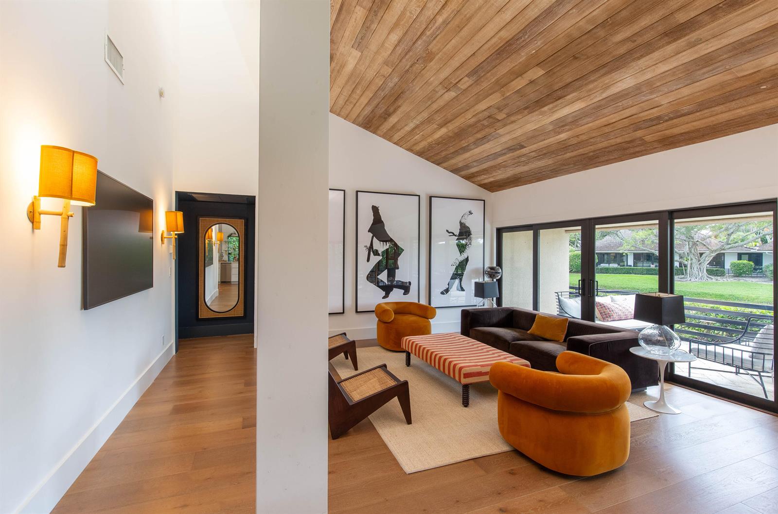 A living room features a wood-paneled vaulted ceiling, orange armchairs, and large glass sliding doors — 11669 Wimbledon Circle, Wellington FL 33414, WELLINGTON, FL