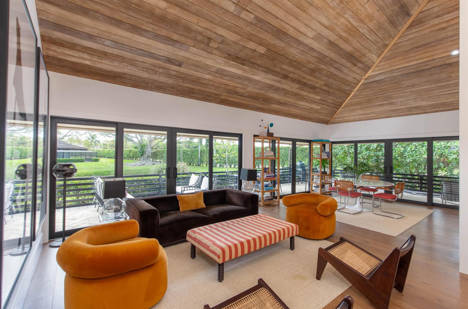 A living room with a vaulted wood ceiling, large glass doors, and mid-century modern furniture — 11669 Wimbledon Circle, Wellington FL 33414, WELLINGTON, FL
