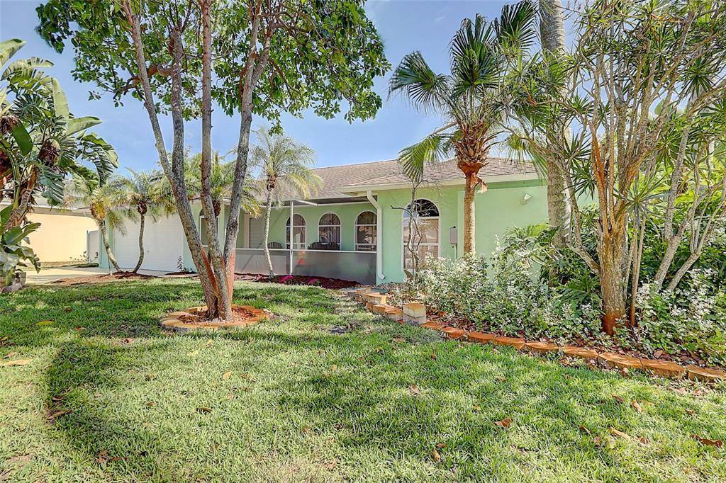 A light green house with a screened-in porch is surrounded by trees and landscaping — 238 SW GROVE AVENUE, PORT ST LUCIE, FL