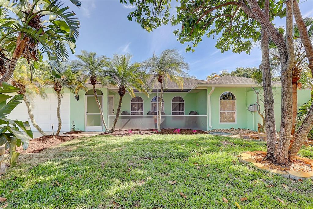 A light green single-story house features a screened-in front porch, arched windows, and palm trees — 238 SW GROVE AVENUE, PORT ST LUCIE, FL
