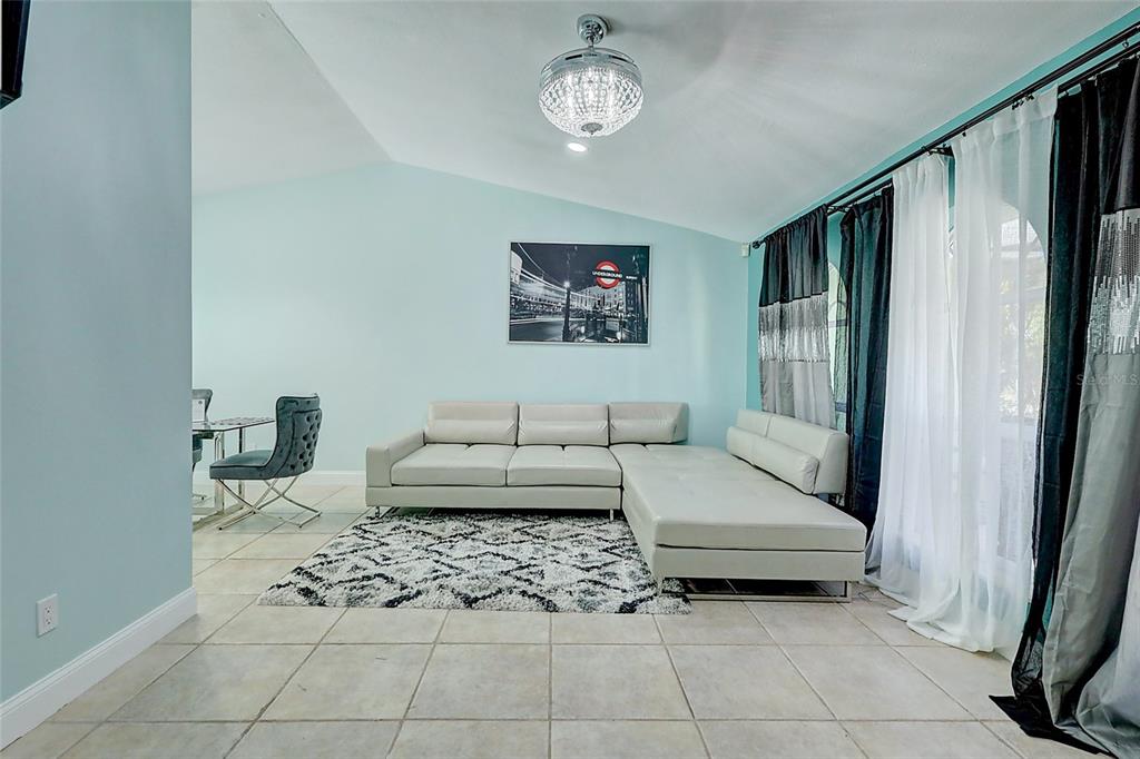 A living room features a light blue wall, a white sectional sofa, and tile flooring — 238 SW GROVE AVENUE, PORT ST LUCIE, FL