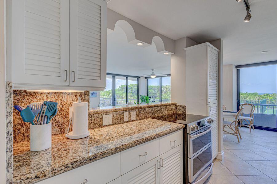 A kitchen with white louvered cabinets, granite countertops, and a view of the outdoors — 5550 N Ocean Drive # 3c, Riviera Beach FL 33404, RIVIERA BEACH, FL