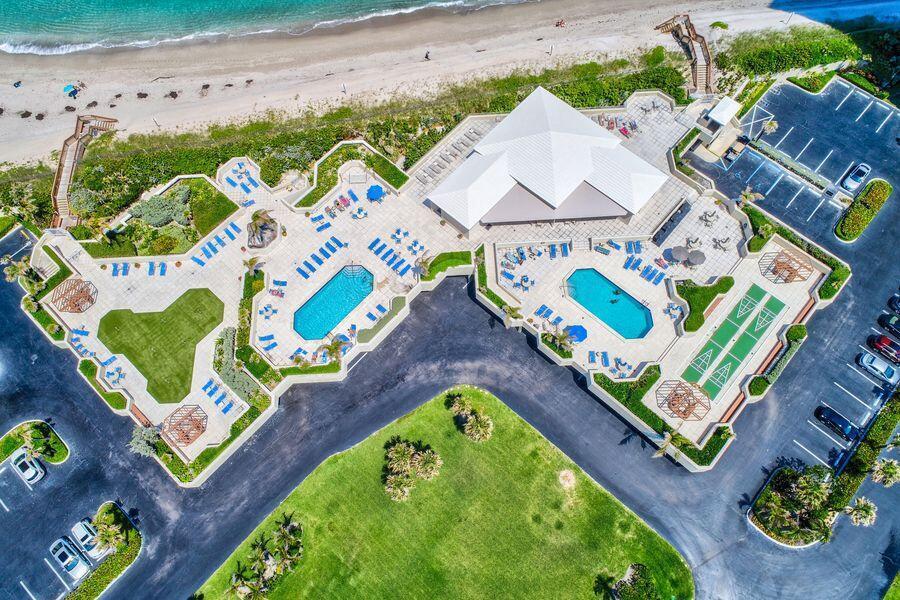 An aerial view shows a beachfront resort with two swimming pools, a clubhouse, and parking — 5550 N Ocean Drive # 3c, Riviera Beach FL 33404, RIVIERA BEACH, FL