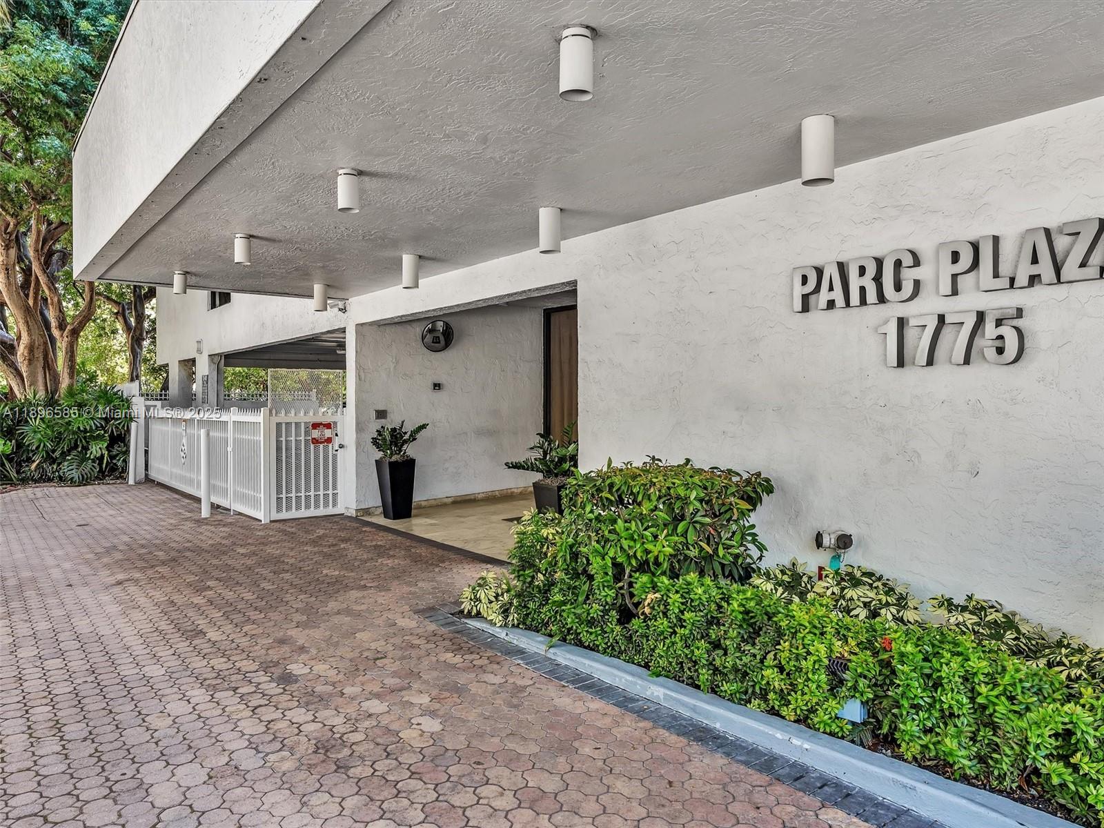 The exterior entrance of a building features a covered driveway, landscaping, and signage — 1775 Washington Ave # 8B, Miami Beach FL 33139, MIAMI BEACH, FL