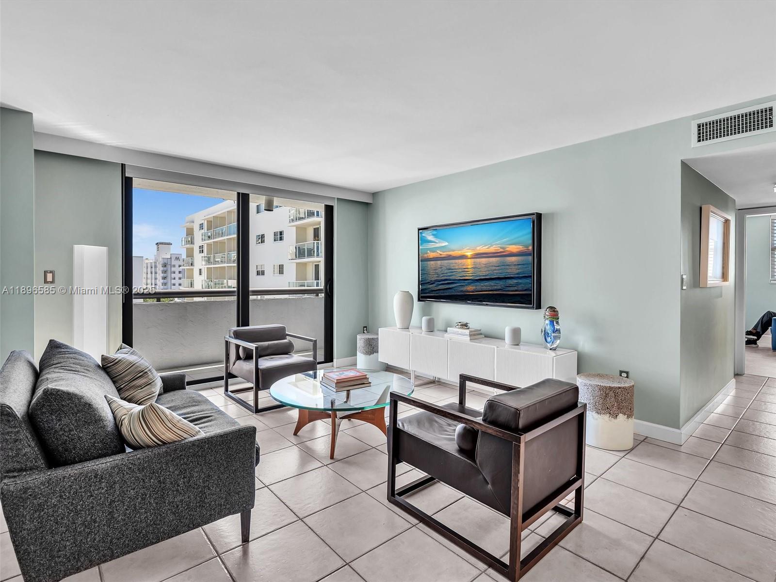 A living room features a grey sofa, two leather chairs, a glass coffee table, and a balcony — 1775 Washington Ave # 8B, Miami Beach FL 33139, MIAMI BEACH, FL