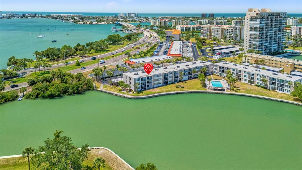 An aerial view shows a multi-story apartment complex situated along a waterfront with a swimming pool — 7401 BAY ISLAND DRIVE S UNIT 337, SOUTH PASADENA, FL