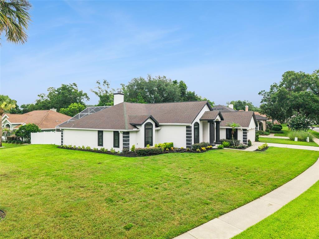 A single-story white house with a dark roof sits on a corner lot with grass — 2331 RIDGESIDE ROAD, APOPKA, FL