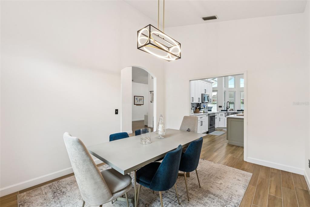 A dining room with a modern light fixture, gray table, and blue and gray chairs — 2331 RIDGESIDE ROAD, APOPKA, FL