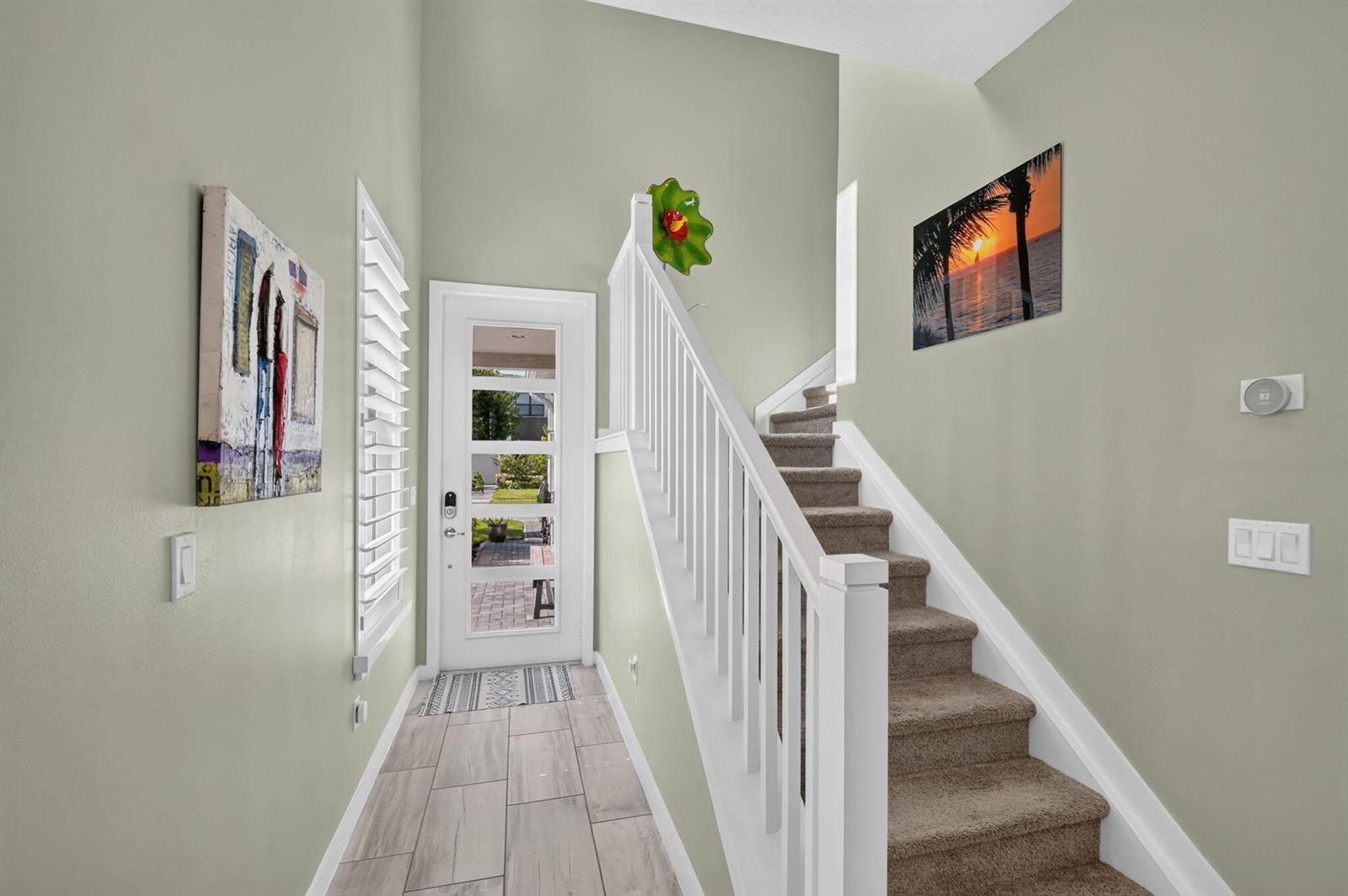 An entryway features light tile flooring, a white front door, and carpeted stairs with railings — 8789 Antarus Drive, Lake Worth FL 33467, LAKE WORTH, FL