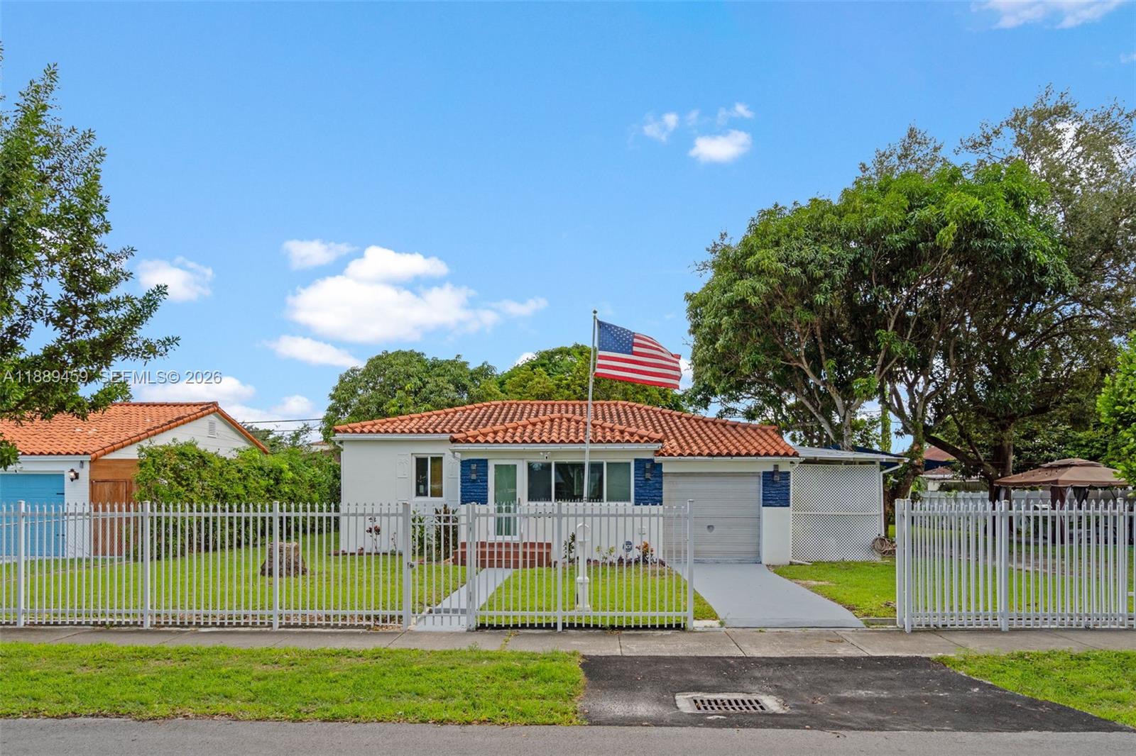 A single-story house with a tiled roof, white fence, and an American flag in front — 5340 SW 5th St, Miami FL 33134, MIAMI, FL