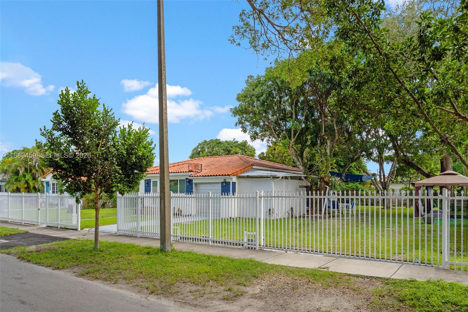 A single-story house with a red tile roof sits behind a white metal fence — 5340 SW 5th St, Miami FL 33134, MIAMI, FL