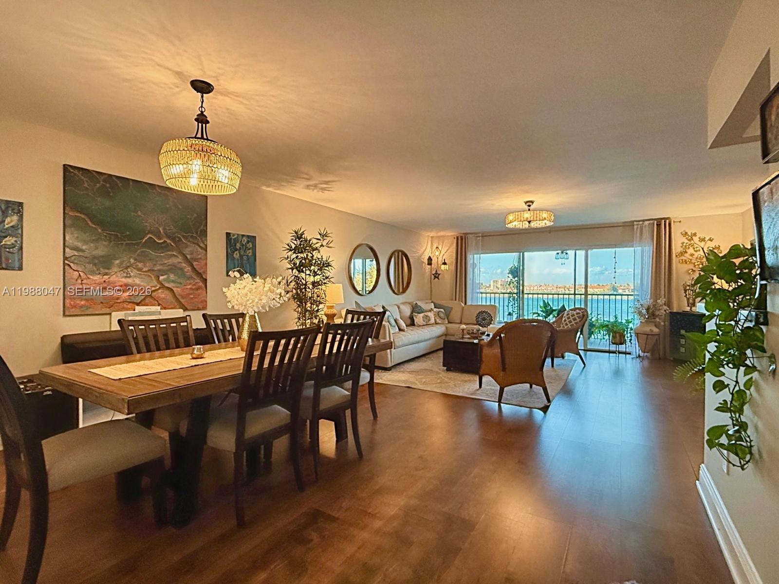 An open-concept living and dining area features wood flooring, a balcony, and waterfront views — 605 Ives Dairy Rd # 7, Miami FL 33179, MIAMI, FL
