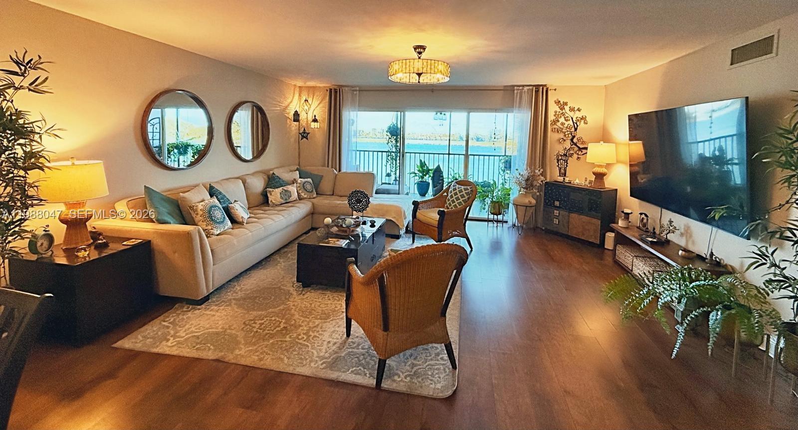 A living room features a beige sectional sofa, wicker chairs, and a large television — 605 Ives Dairy Rd # 7, Miami FL 33179, MIAMI, FL