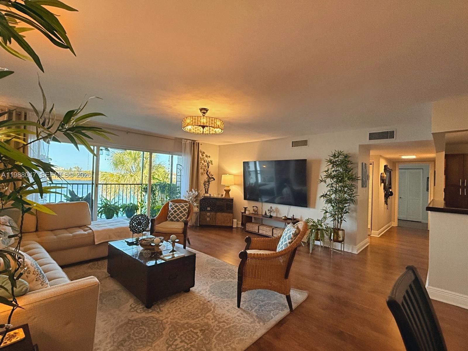 A living room features a sectional sofa, wicker chairs, a television, and a balcony view — 605 Ives Dairy Rd # 7, Miami FL 33179, MIAMI, FL