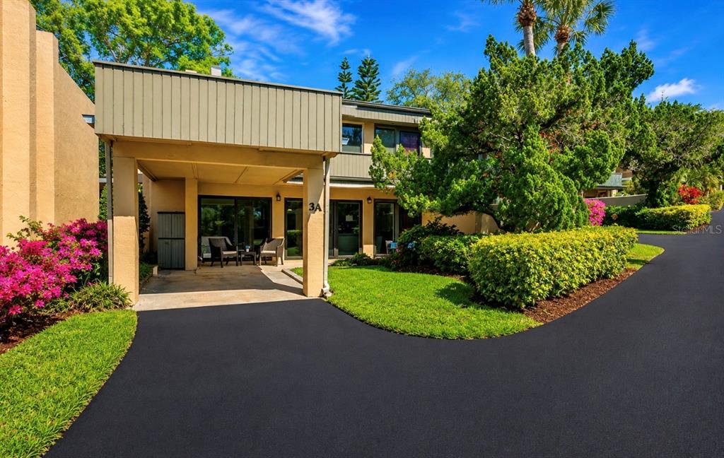 A two-story building with a covered carport, a paved driveway, and landscaped green space — 601 W OLD US HIGHWAY 441 UNIT 3A, MOUNT DORA, FL