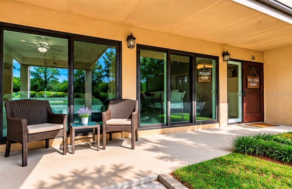 A patio features two wicker chairs, a small table, sliding glass doors, and a front door — 601 W OLD US HIGHWAY 441 UNIT 3A, MOUNT DORA, FL
