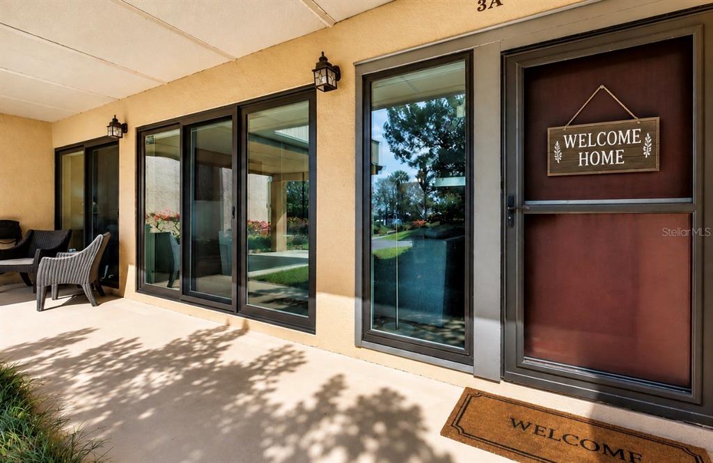 A covered patio features a glass door with a welcome sign and sliding glass doors — 601 W OLD US HIGHWAY 441 UNIT 3A, MOUNT DORA, FL