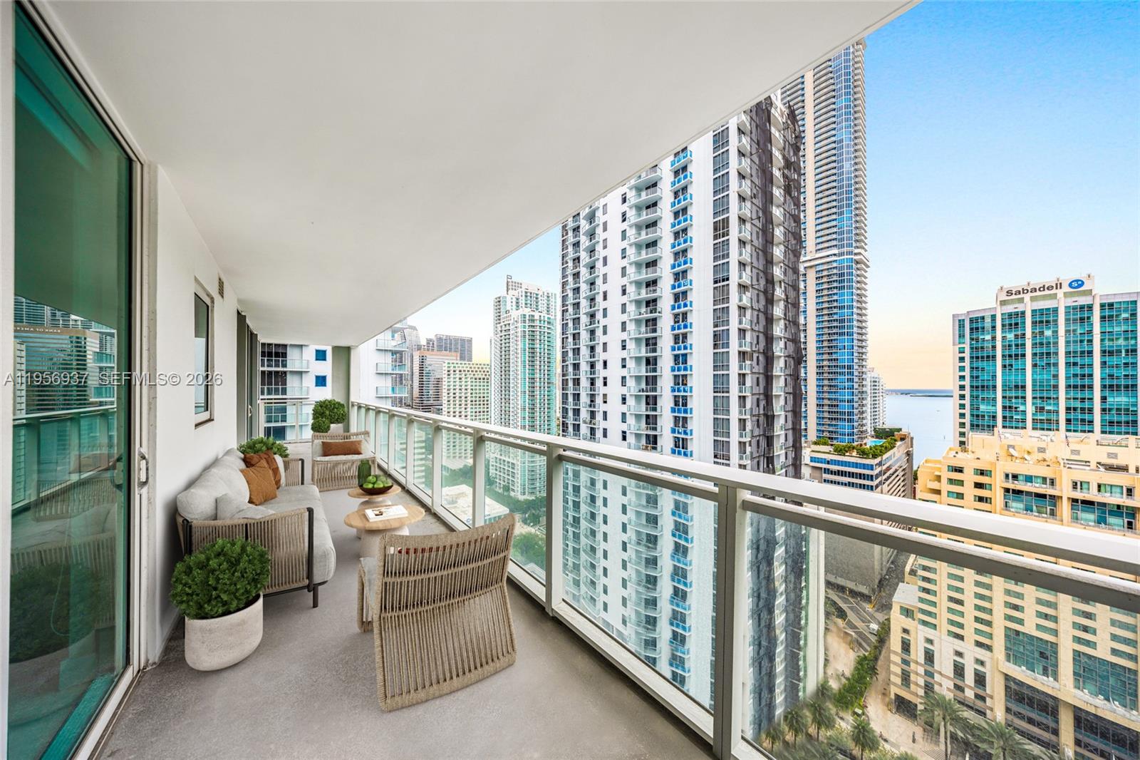 A high-rise balcony features outdoor seating, a glass railing, and views of surrounding city skyscrapers — 1080 Brickell Ave # 2708, Miami FL 33131, MIAMI, FL