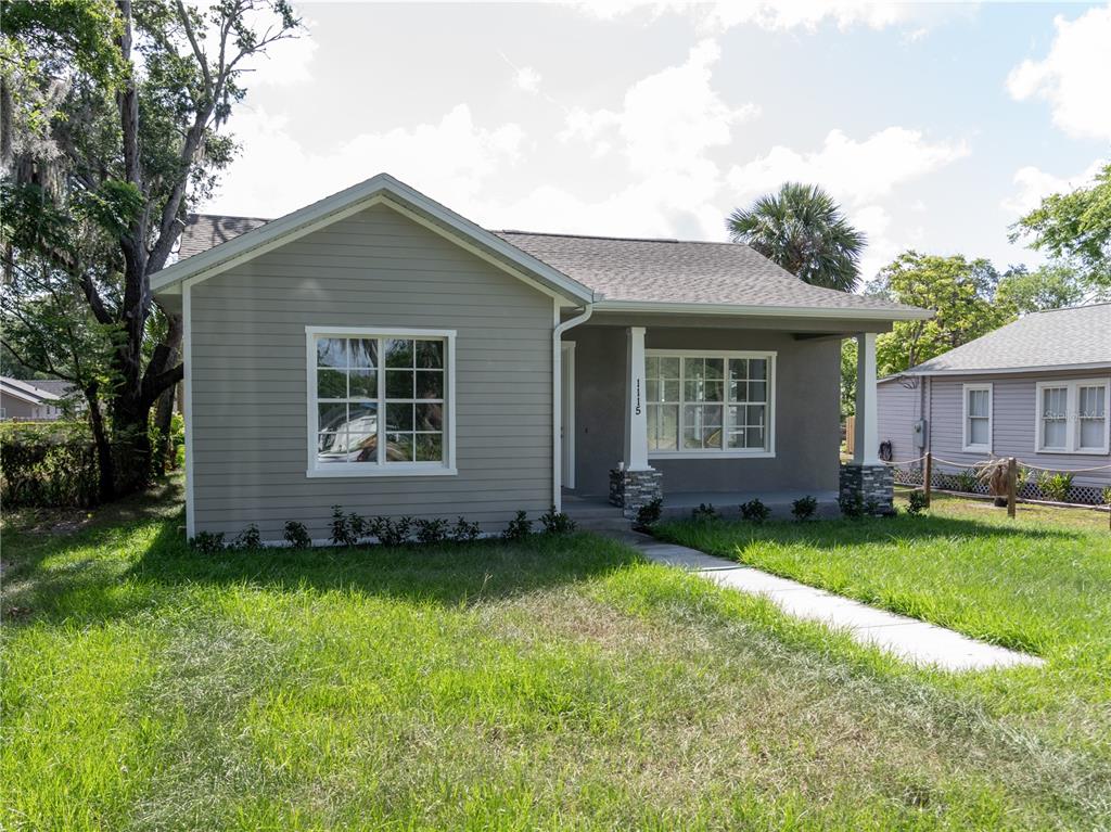 A gray single-story house with a front porch, white trim, and a concrete walkway — 1115 HICKORY, SANFORD, FL