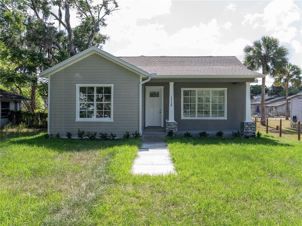 A single-story house with gray siding, a front porch, and a concrete walkway — 1115 HICKORY, SANFORD, FL