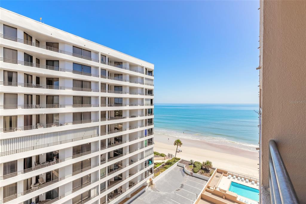 A high-angle view shows a multi-story apartment building overlooking a beach and the ocean — 3023 S ATLANTIC AVENUE UNIT 9010, DAYTONA BEACH, FL