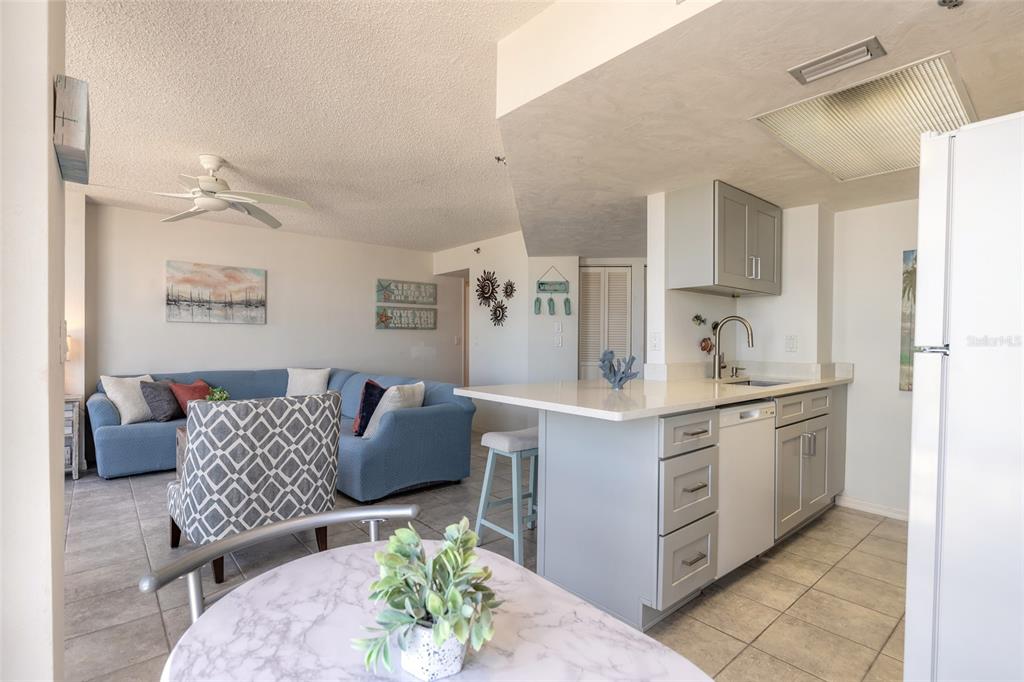 An open-concept living room and kitchen featuring a blue sectional sofa and a breakfast bar — 3023 S ATLANTIC AVENUE UNIT 9010, DAYTONA BEACH, FL
