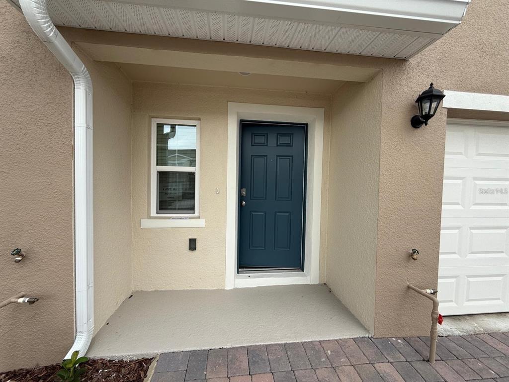 The exterior entryway features a blue front door, a single window, and a concrete porch — 2926 HUDSON HAMMOCK WAY, BEND, HARMONY, FL