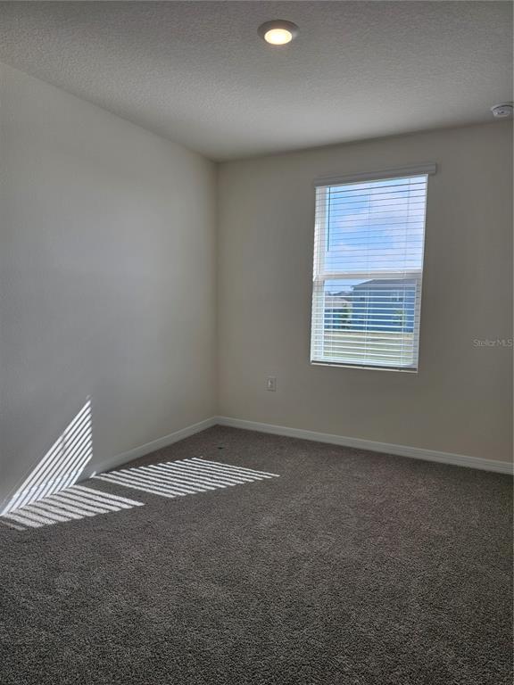 An empty bedroom features beige walls, gray carpeting, a single window with blinds, and a ceiling light — 2926 HUDSON HAMMOCK WAY, BEND, HARMONY, FL