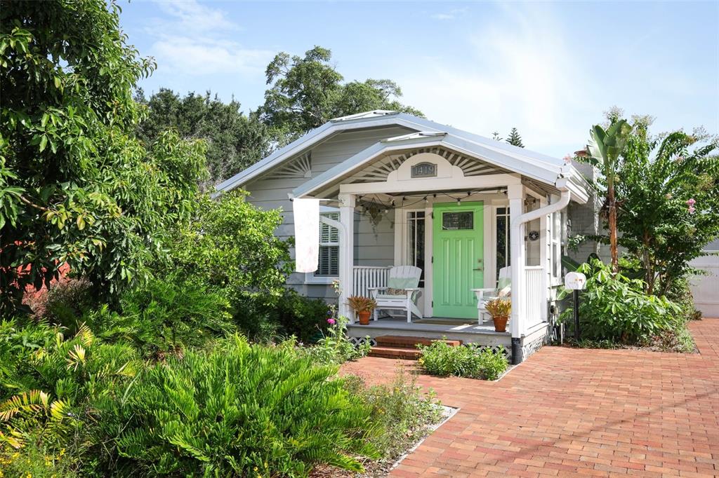 A light gray bungalow features a bright green front door and a covered brick porch — 1419 CANTON STREET, ORLANDO, FL