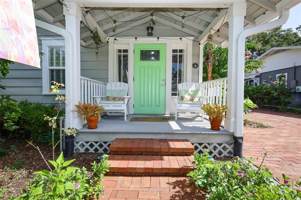A front porch features a light green door, two white chairs, and brick steps — 1419 CANTON STREET, ORLANDO, FL