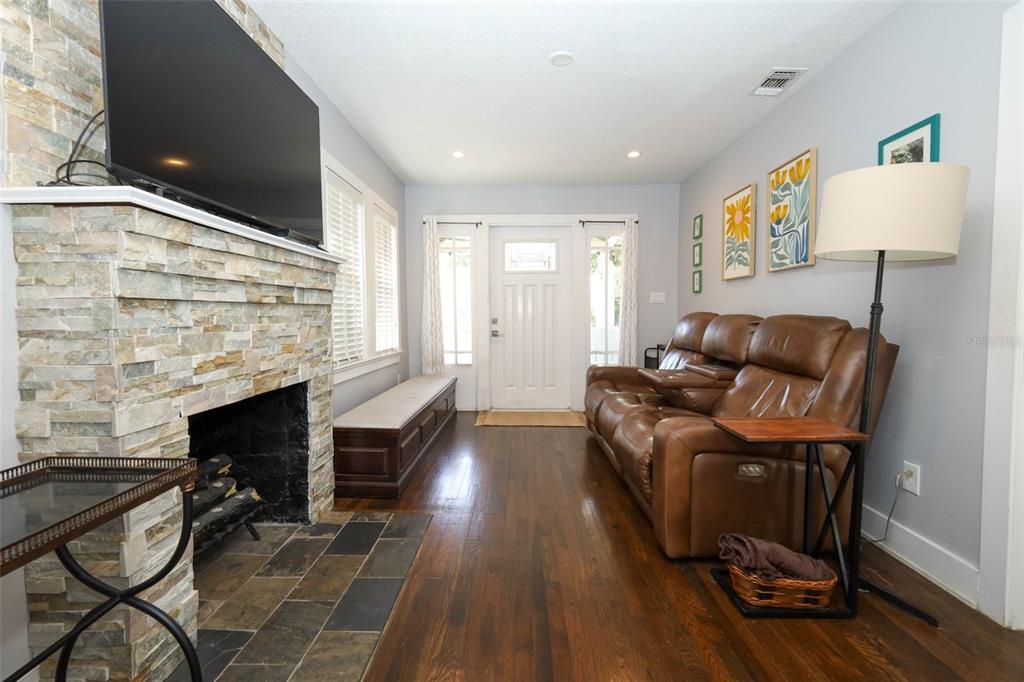 A living room features a stone fireplace, brown leather sofa, and hardwood flooring — 1419 CANTON STREET, ORLANDO, FL
