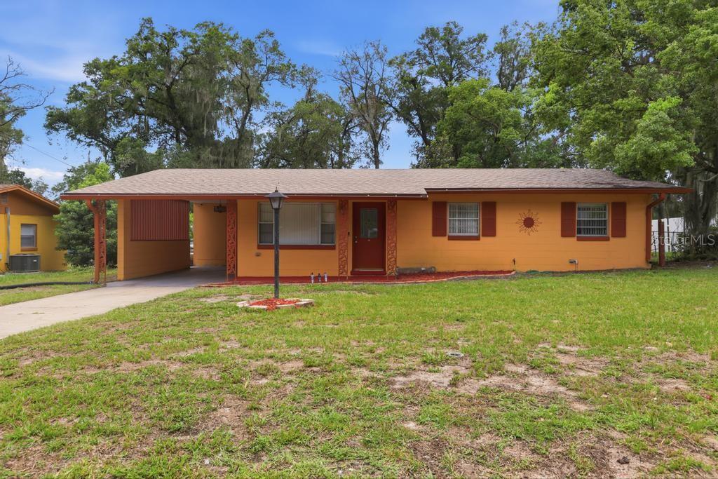 A single-story orange house with a carport, brown shutters, and a front lawn — 812 W FRANKLIN AVENUE, DELAND, FL