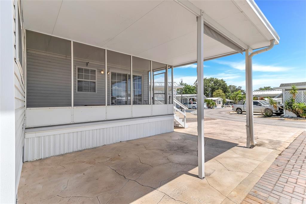 A covered concrete patio sits adjacent to a screened-in porch with white siding — 300 SKY CREST LOOP, DAVENPORT, FL